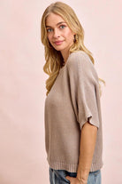 Woman wearing a beige sweater against a pink background