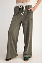 Woman wearing a green outfit with a green and white top on a plain background