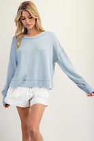 Woman wearing a light blue sweater and white shorts on a plain background