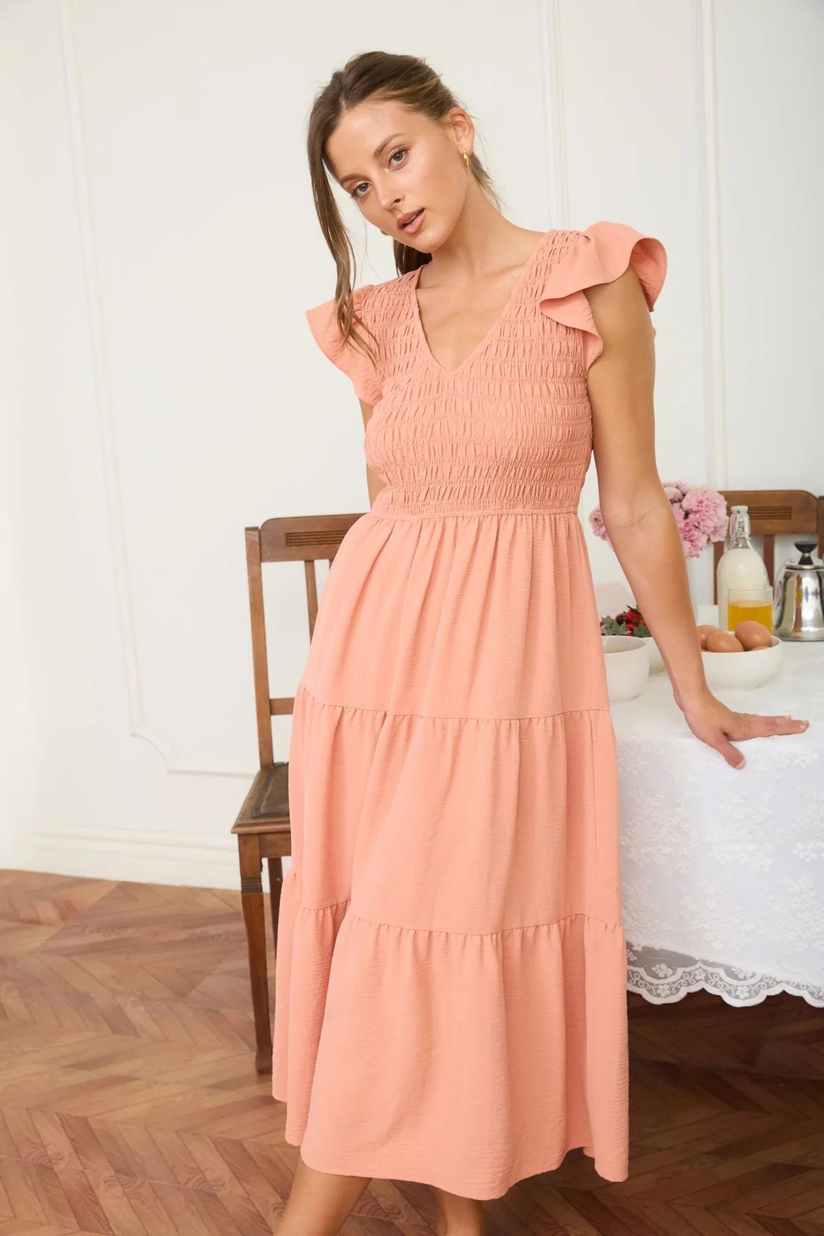 Woman wearing a peach-colored dress in a dining room setting