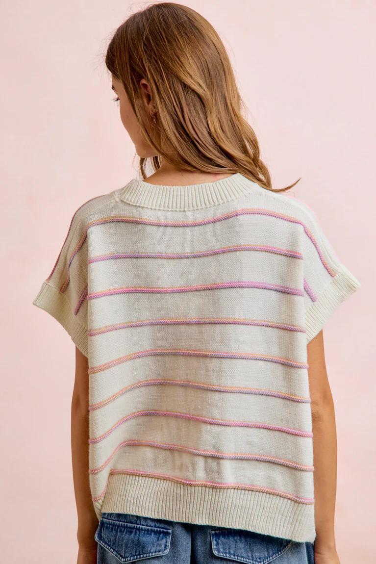 Woman wearing a striped sweater with a pink background