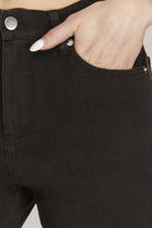 Close-up of a person wearing black jeans with a hand in the pocket.