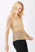 Woman wearing a beige long-sleeve top on a white background