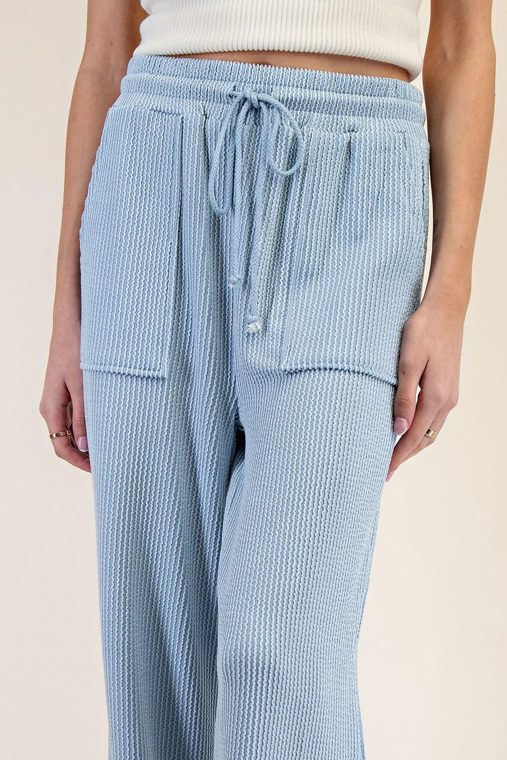 Light blue textured pants with drawstring waist on a beige background