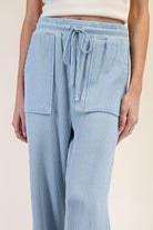 Light blue textured pants with drawstring waist on a beige background