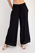 Black wide-leg pants worn by a person on a white background
