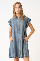 Woman wearing a denim dress with ruffled sleeves on a white background