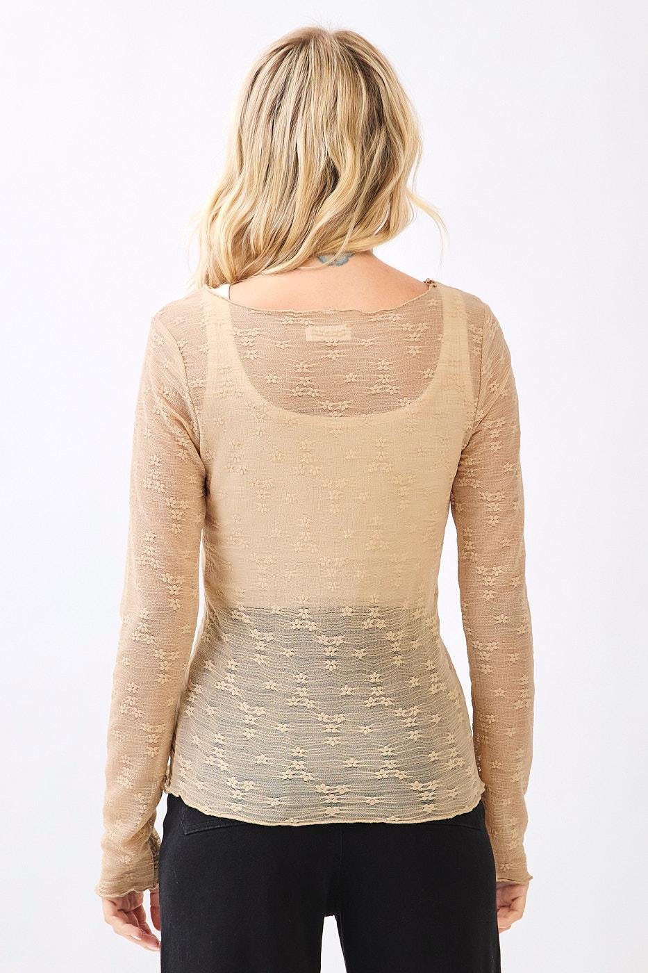 Woman wearing a beige long-sleeve top with a subtle pattern on a white background