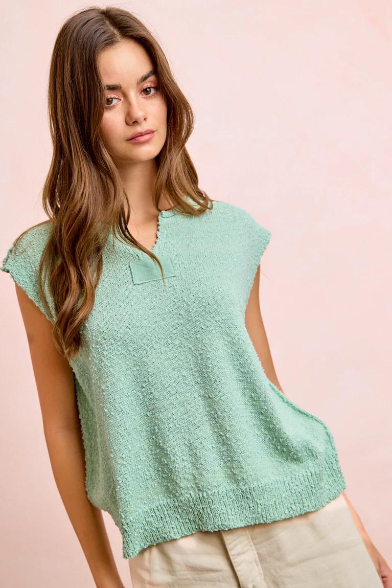 Woman wearing a light green sleeveless top against a pink background
