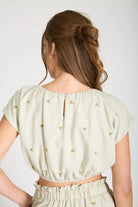 Woman wearing a light-colored blouse with small patterns on a plain background