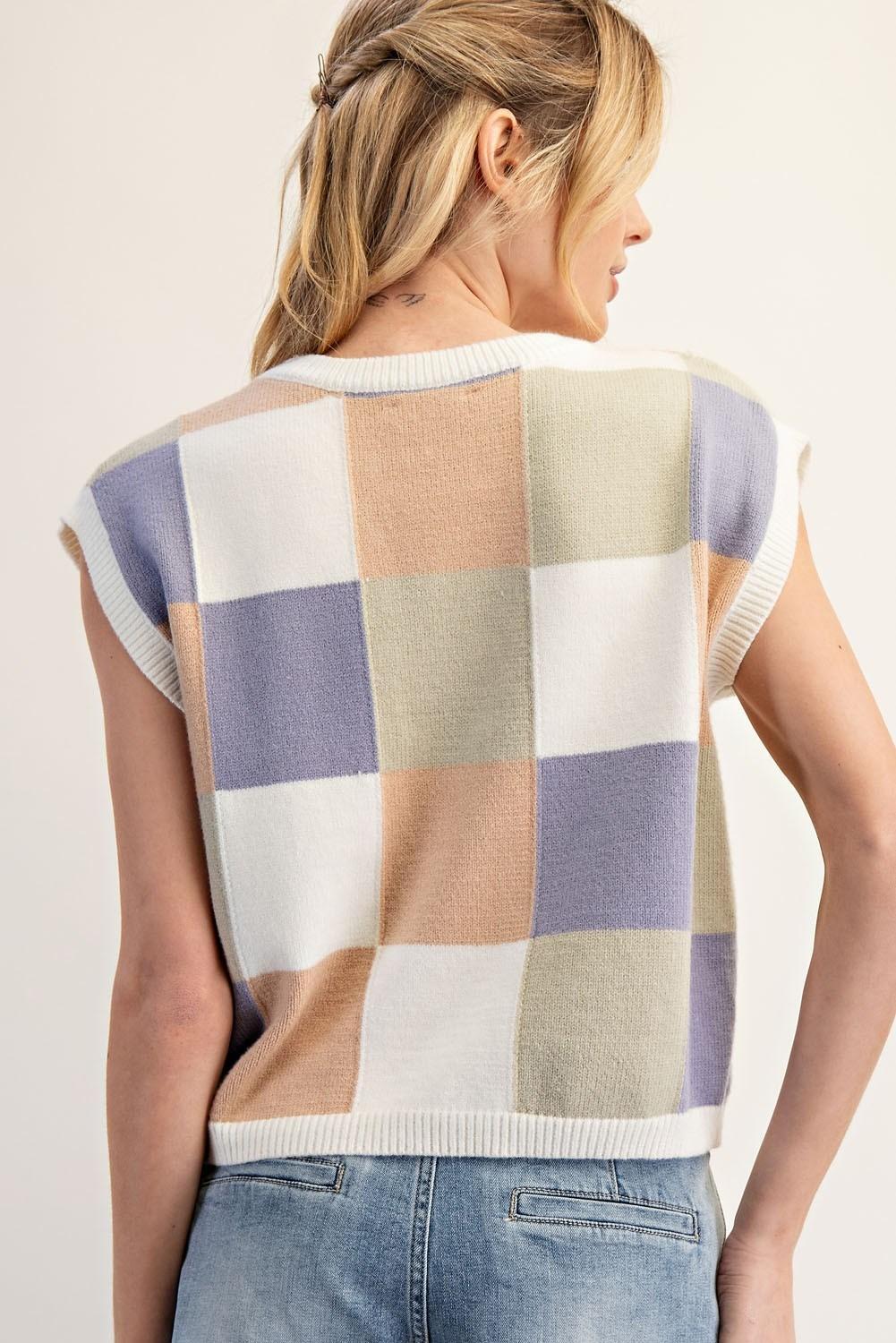 Woman wearing a sleeveless checkered sweater with a neutral background