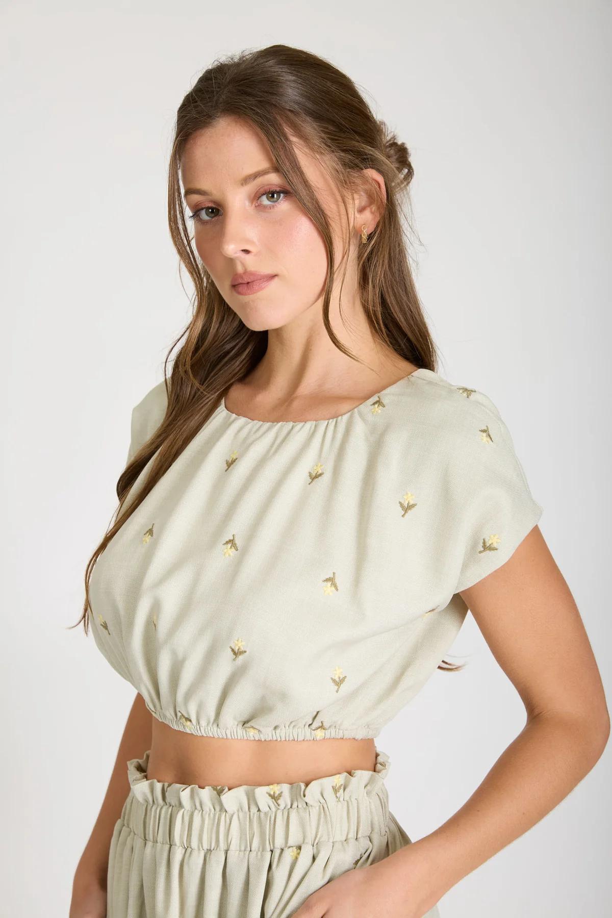 Woman wearing a light green top with small decorative elements on a white background