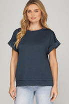 Woman wearing a navy blue top and light blue jeans on a gray background