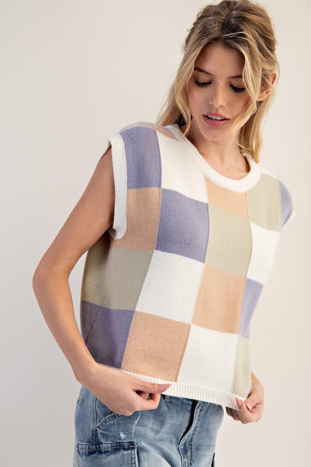 Woman wearing a sleeveless checkered sweater with a plain background