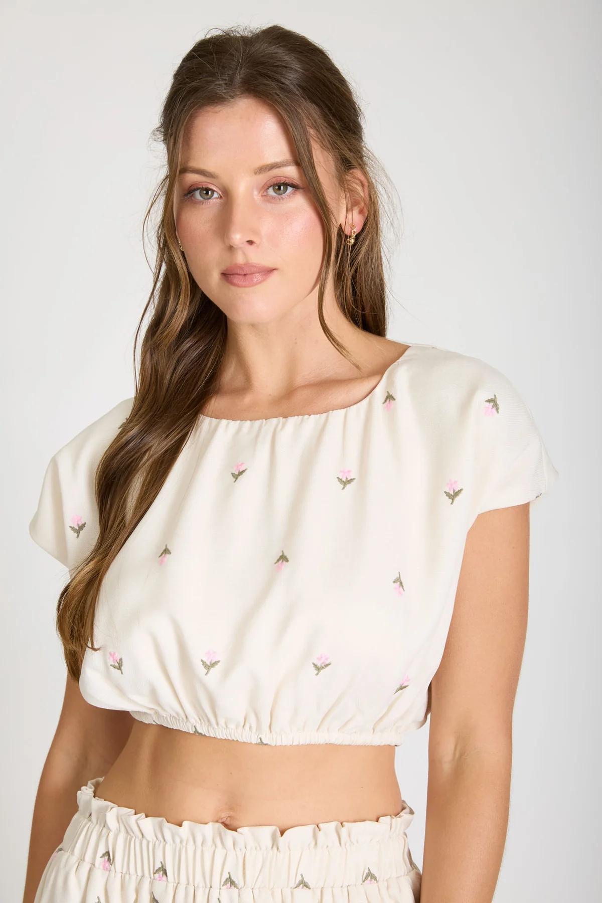 Woman wearing a white blouse with small patterns on a plain background