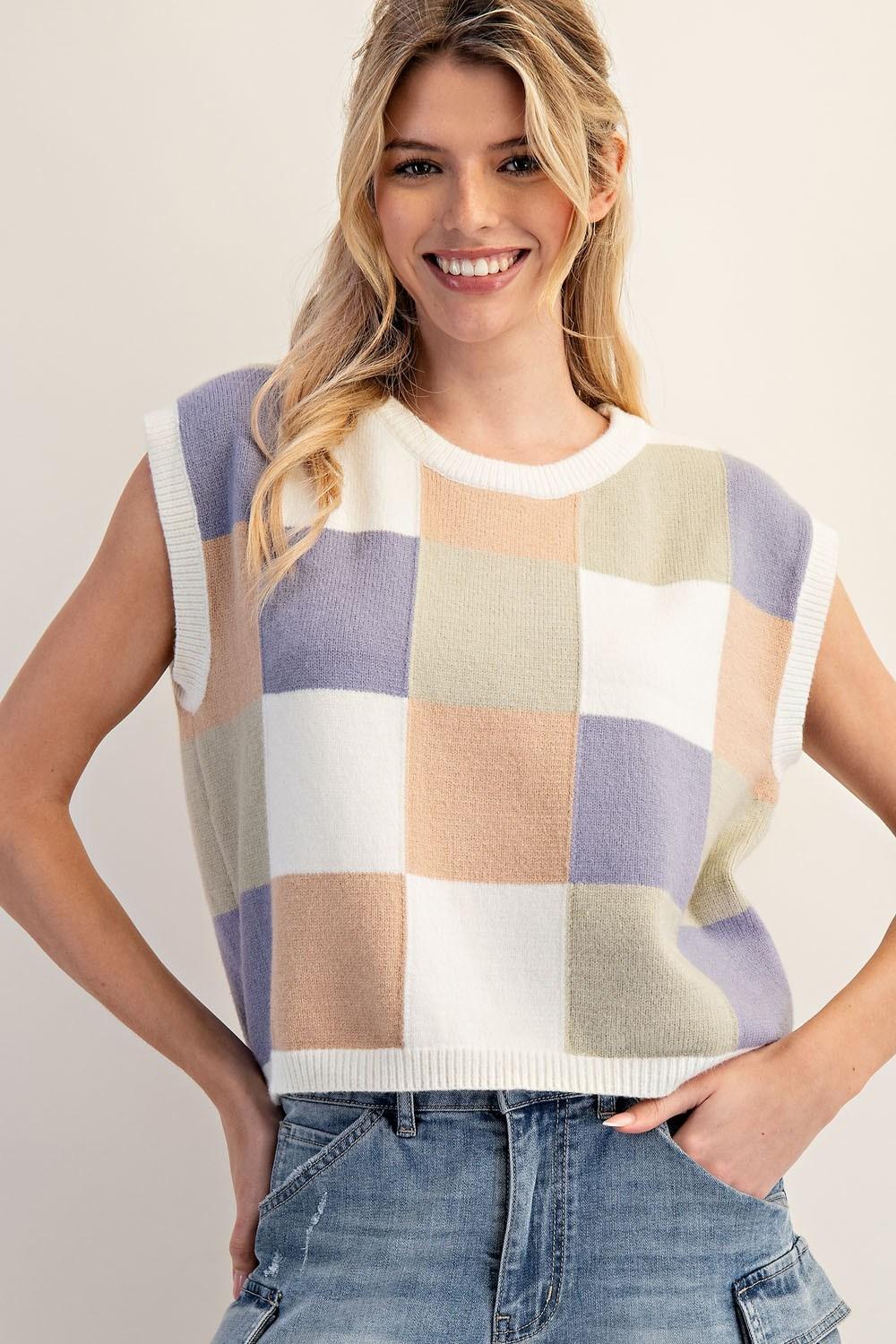 Woman wearing a checkered sleeveless sweater against a plain background