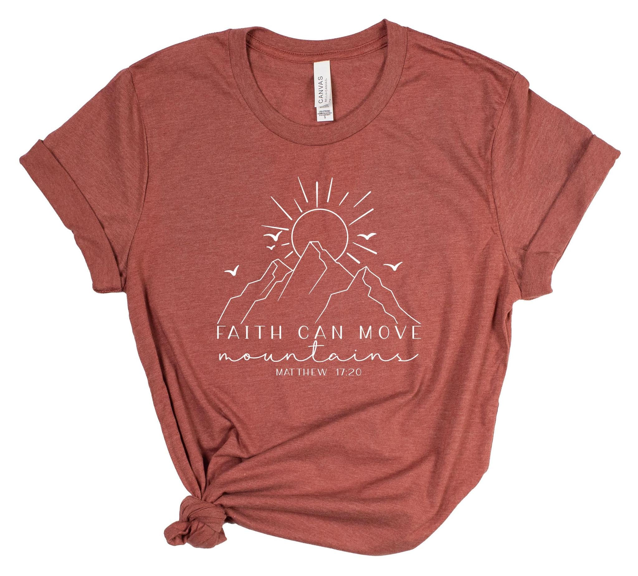 Red t-shirt with mountain graphic and 'Faith Can Move Mountains' text on a white background