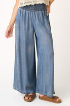 Denim wide-leg pants worn by a person on a white background
