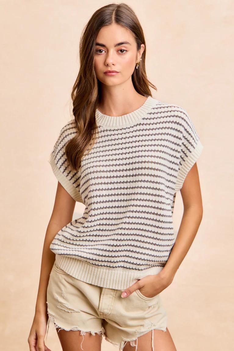 Woman wearing a striped sweater and shorts on a beige background