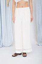 Person wearing white pants with a striped curtain background