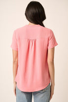 Person wearing a pink blouse with a plain background