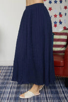 Person wearing a navy blue skirt with a colorful star-patterned curtain in the background.