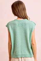 Woman wearing a light green sleeveless top against a pink background