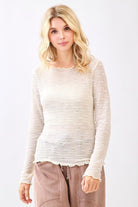 Woman wearing a light-colored sweater and pants on a white background