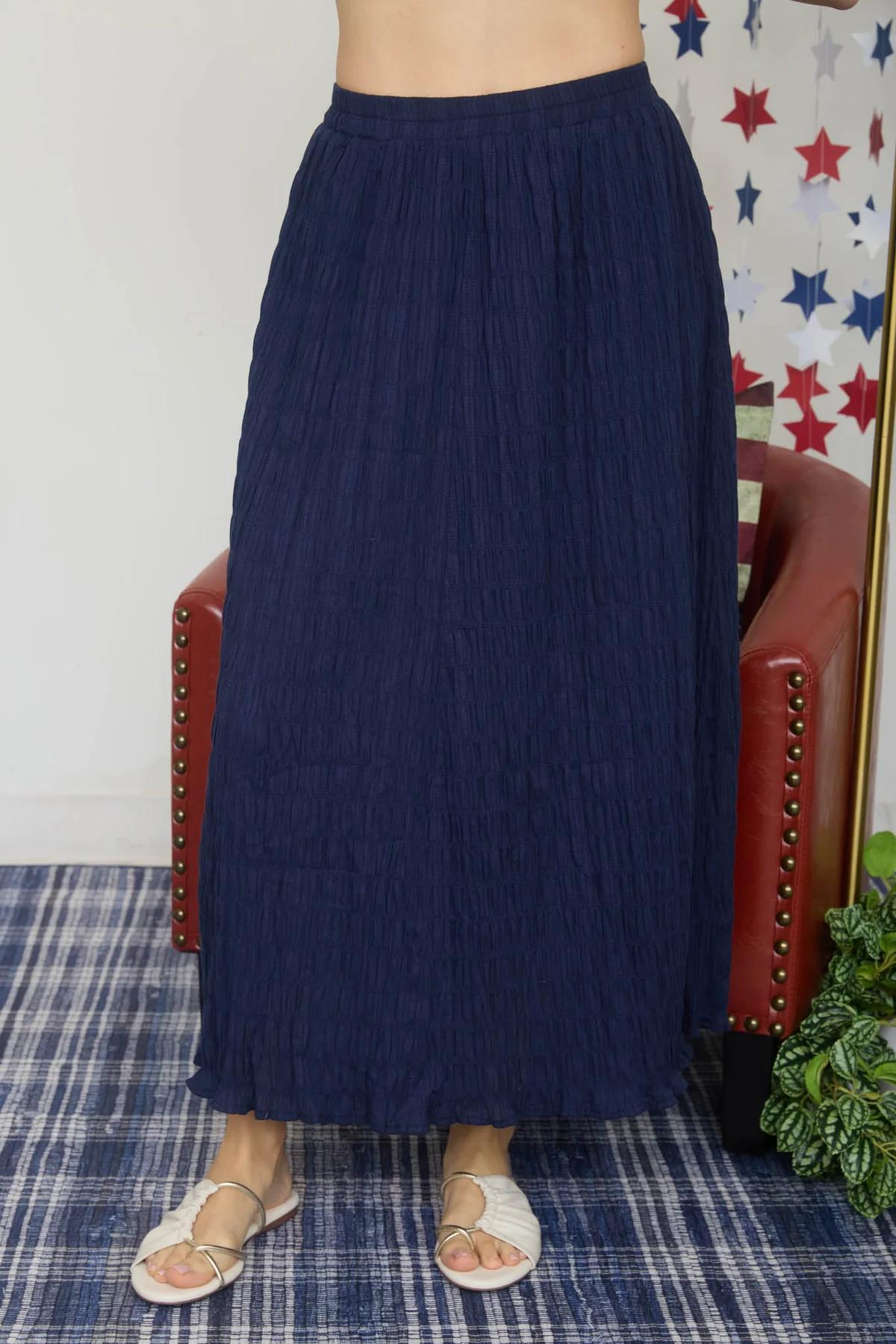 Person wearing a navy blue skirt standing in a room with a plaid carpet and star-patterned wallpaper.