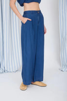 Person wearing blue wide-leg jeans with a striped curtain background